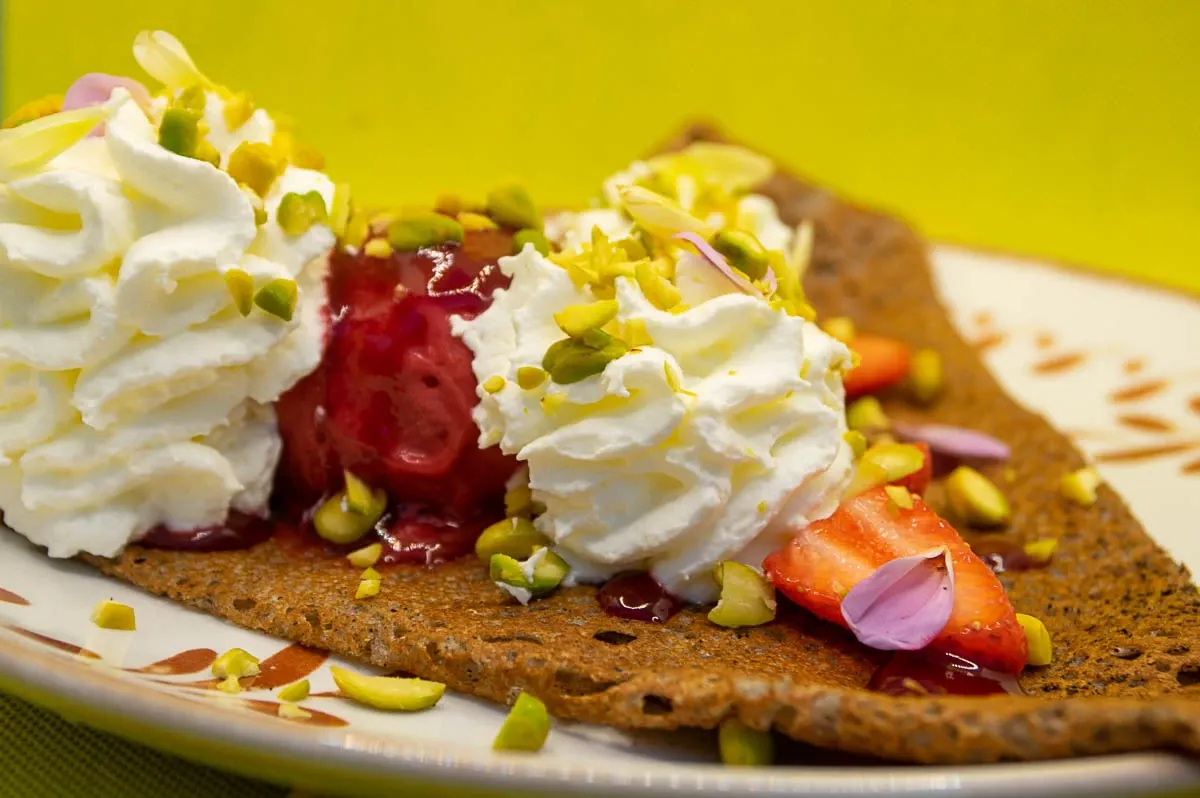Crêpe garnie de chantilly, fruits rouges et éclats de pistache