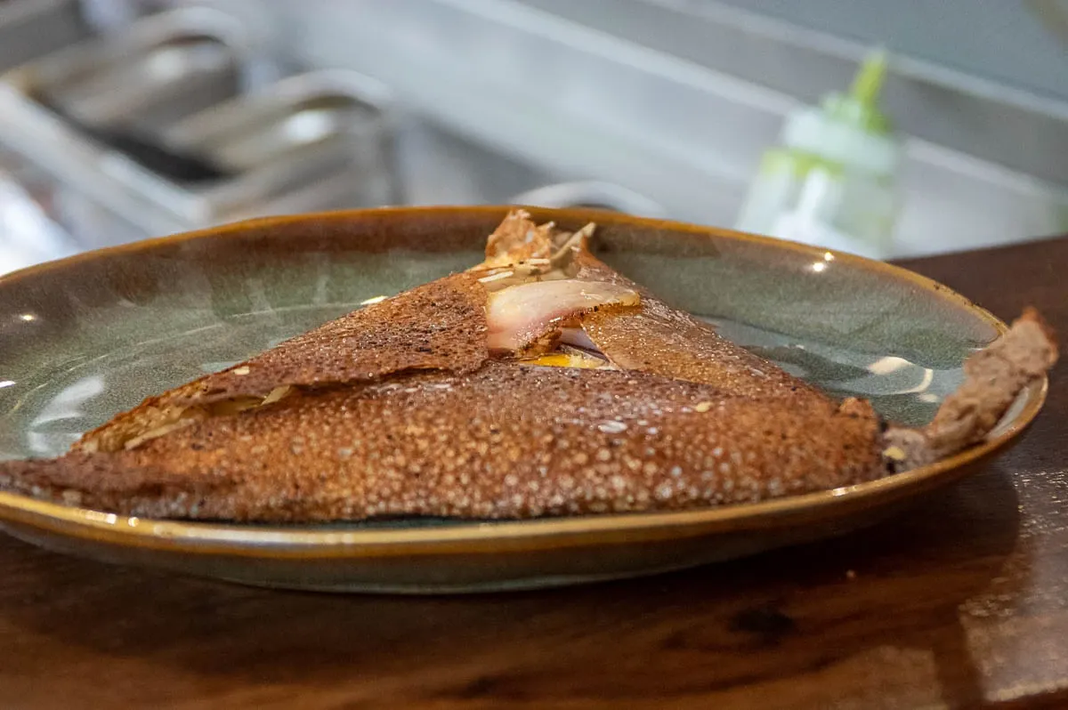 Galette de blé noir pliée, servie dans une assiette en grès