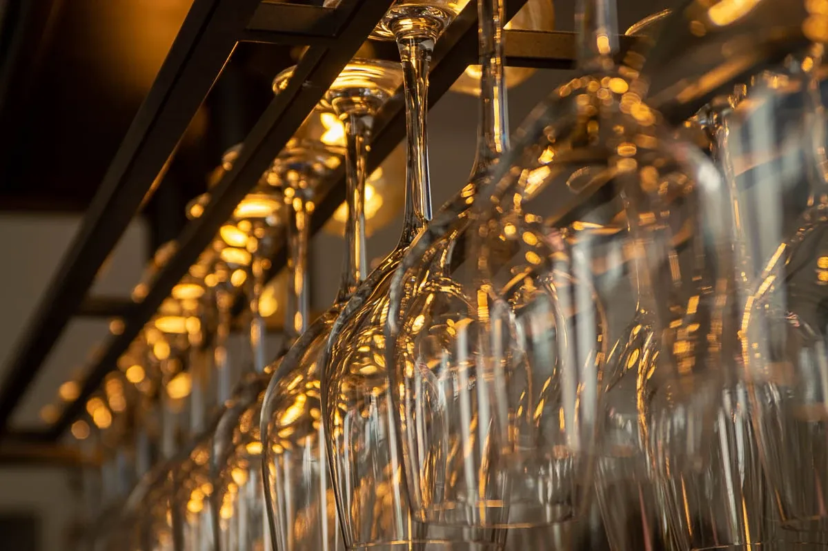Verres à pied suspendus au-dessus du bar, à contre-jour